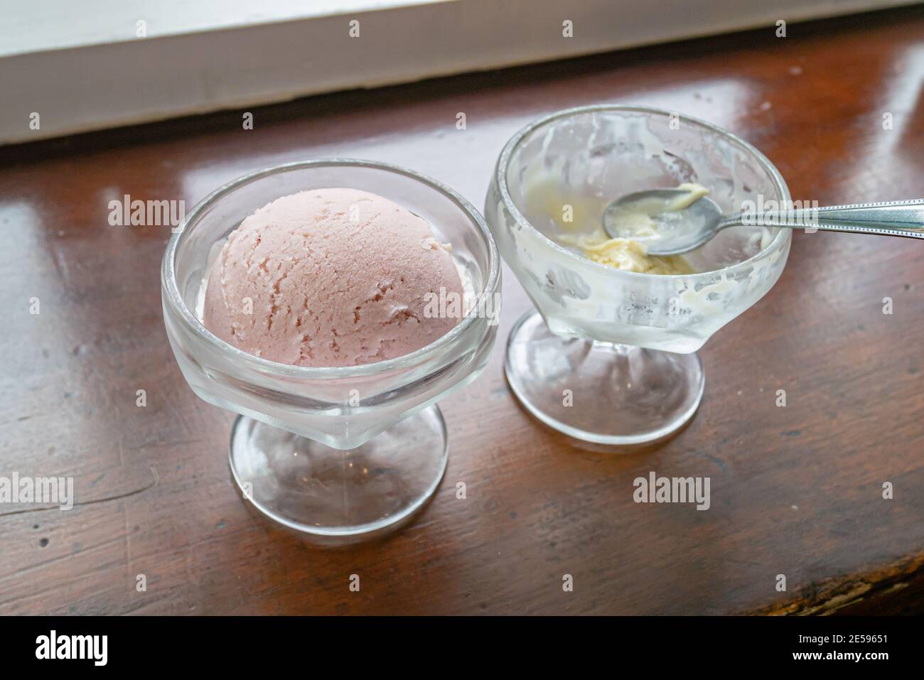 Il primo piano di gustosi scoop fatti in casa gelato alla fragola fresco in tazza di vetro su sfondo tavola di legno vintage. Foto Stock