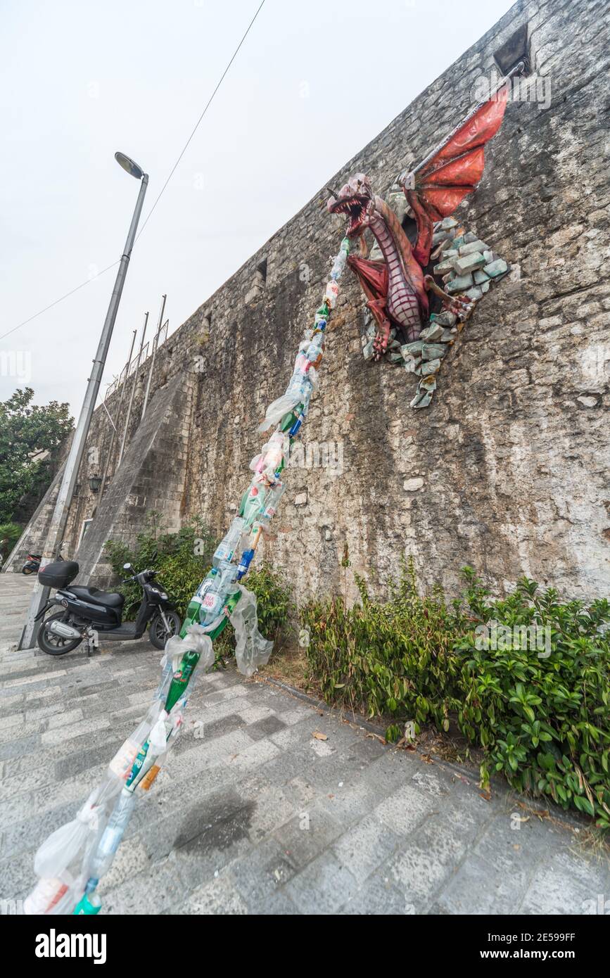 Un modello un drago attaccato al muro di Kotor Fort sprigola i rifiuti di plastica come un messaggio ambientale circa l'inquinamento per i passanti da vedere. Foto Stock