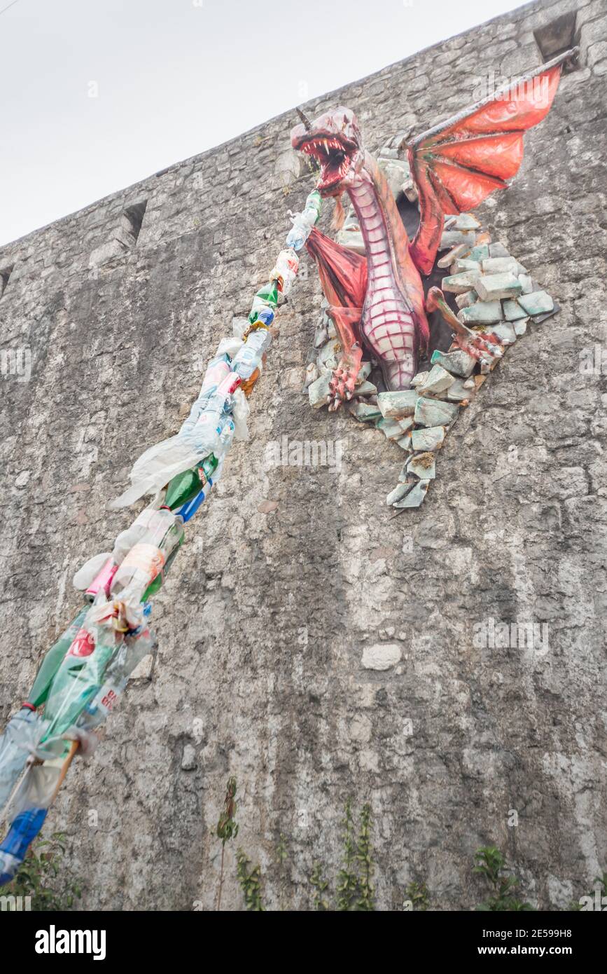 Un modello un drago attaccato al muro di Kotor Fort sprigola i rifiuti di plastica come un messaggio ambientale circa l'inquinamento per i passanti da vedere. Foto Stock