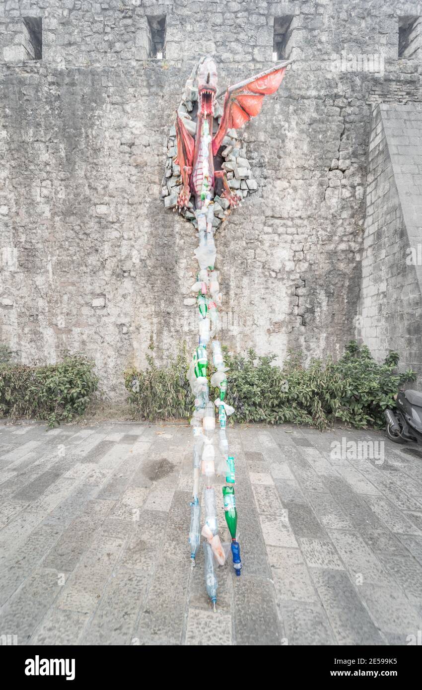 Un modello un drago attaccato al muro di Kotor Fort sprigola i rifiuti di plastica come un messaggio ambientale circa l'inquinamento per i passanti da vedere. Foto Stock