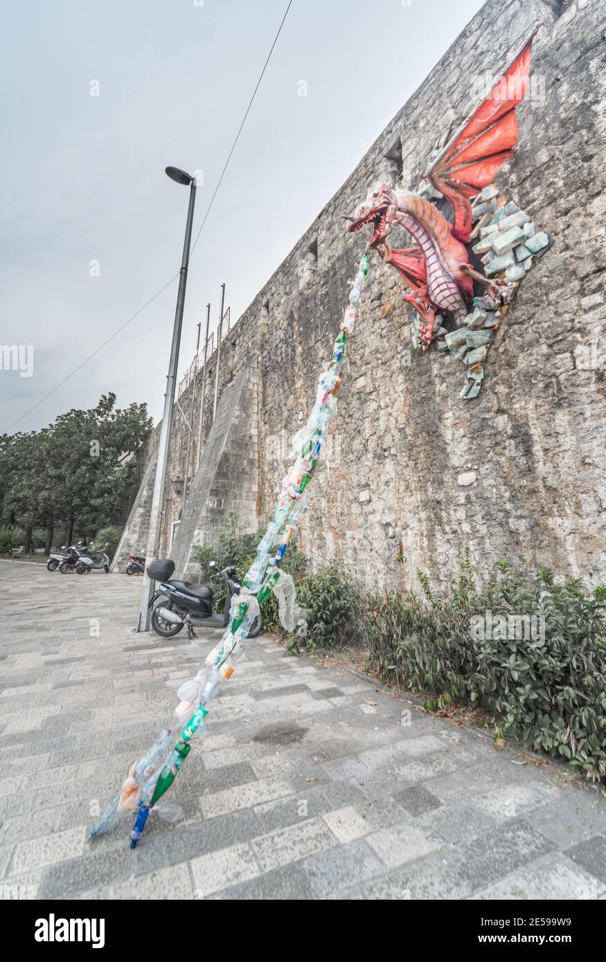 Un modello un drago attaccato al muro di Kotor Fort sprigola i rifiuti di plastica come un messaggio ambientale circa l'inquinamento per i passanti da vedere. Foto Stock