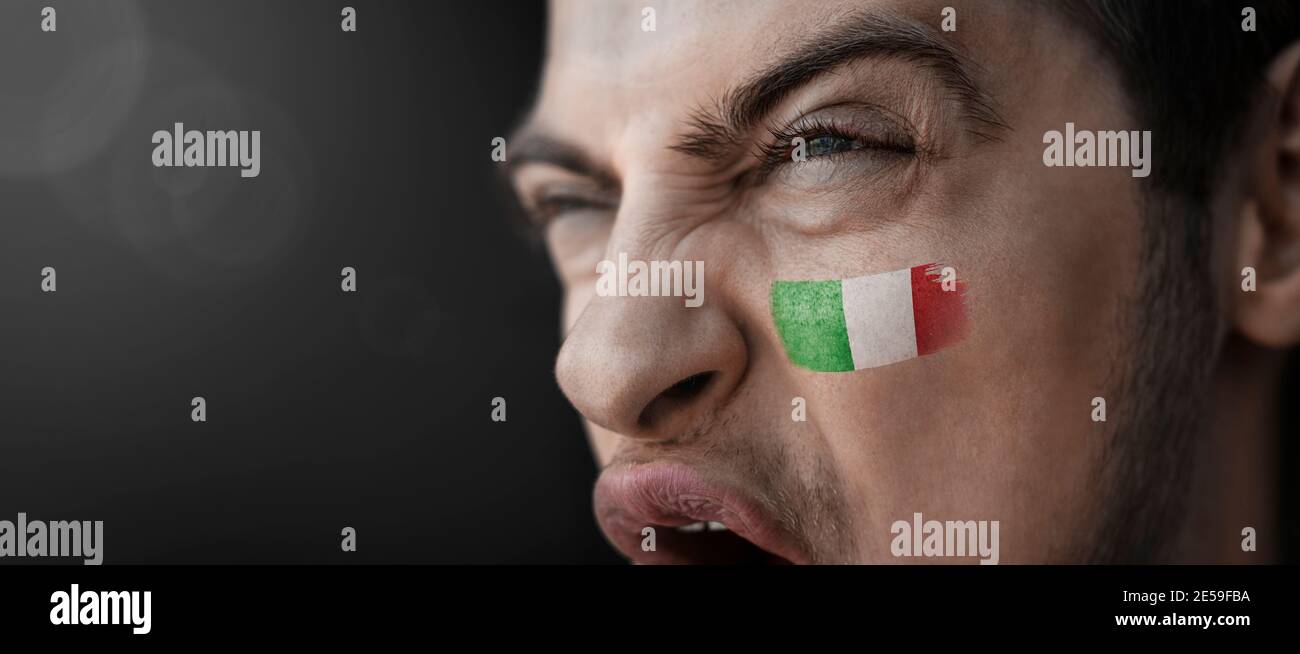 Un uomo urlante con l'immagine del nazionale italiano bandiera sul viso Foto Stock