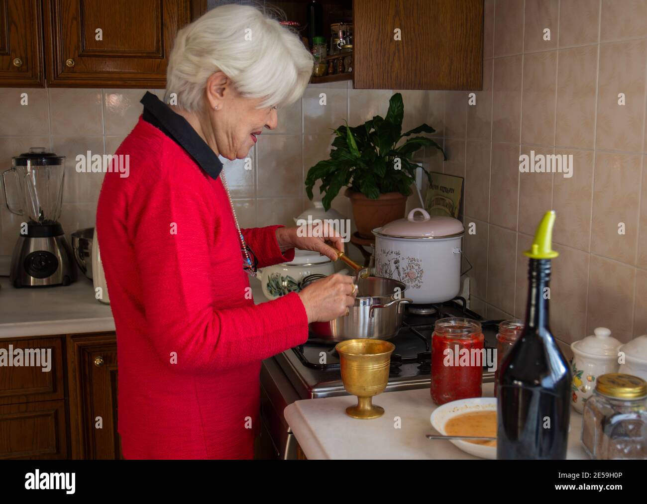 Donna in maglione rosso che prepara zuppa in cucina. Donna a fuoco selettivo in pullover rosso. Tradizionale tarhana di sapone turco. Foto Stock