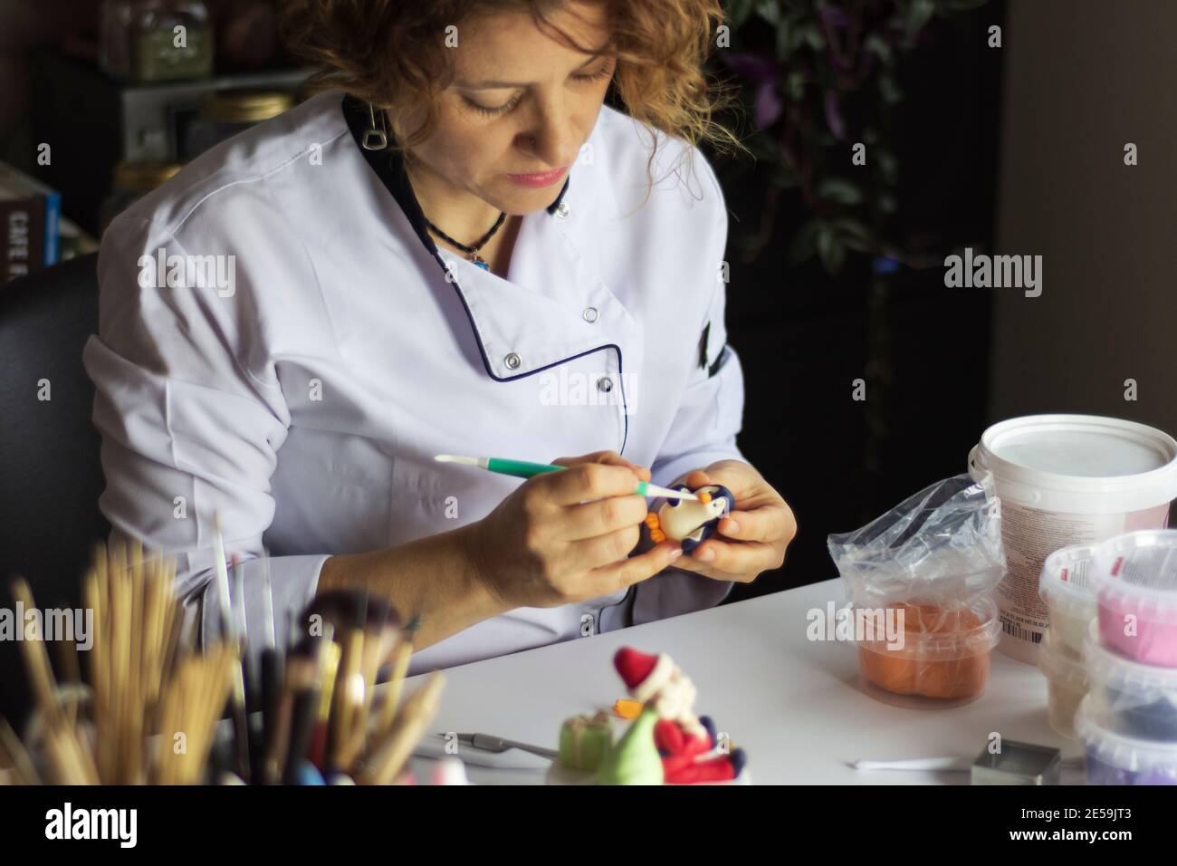 Processo di decorazione della torta. Baker usa gli strumenti per scolpire i modelli fondenti: Arte commestibile, disegno della torta, decorazione della torta. Messa a fuoco selettiva degli attrezzi anteriori e della mano Foto Stock