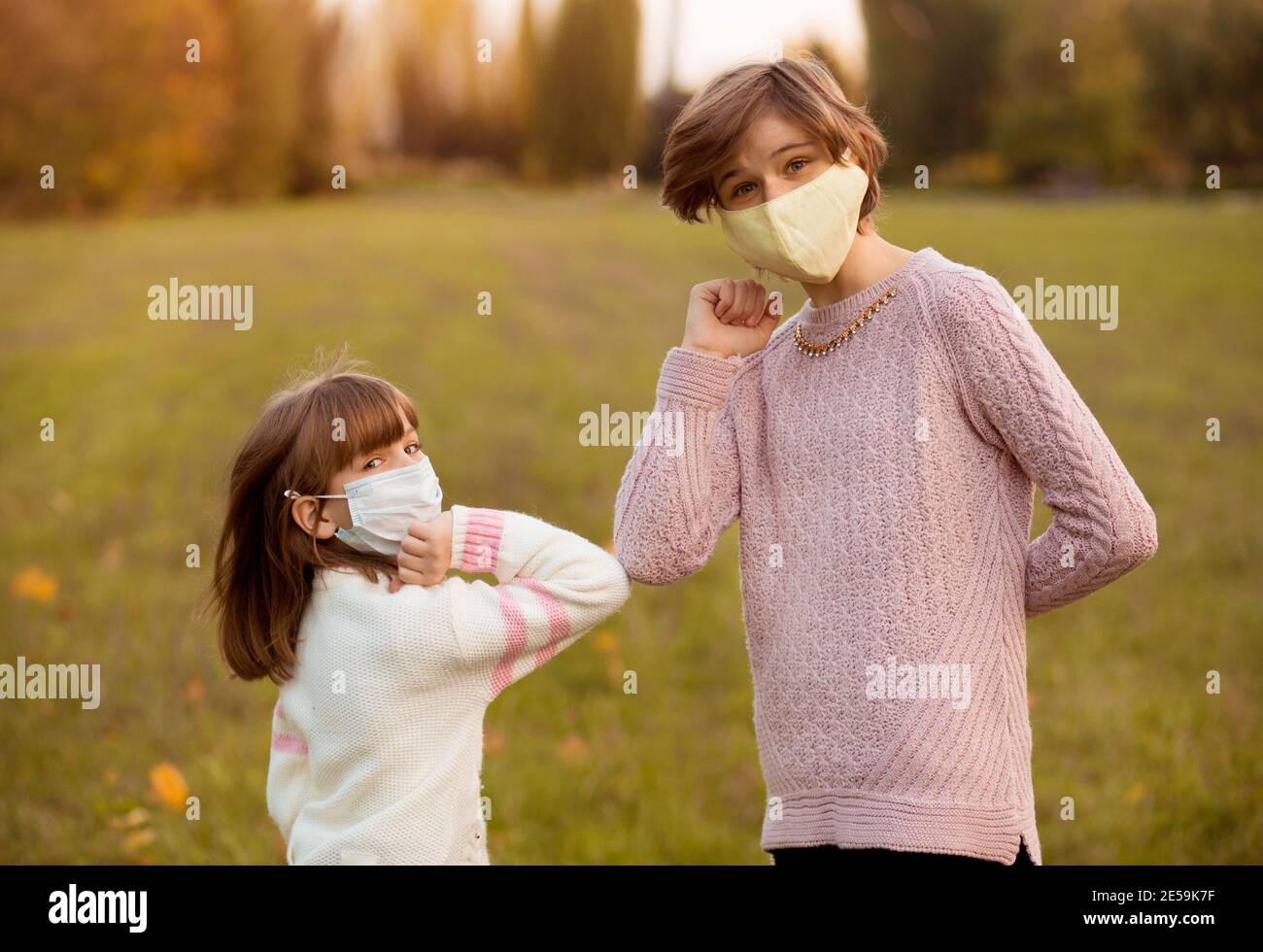 Due ragazze si abbaccano i gomiti per evitare il coronavirus all'aperto. Saluto durante l'epidemia di coronavirus. Concetto di assistenza sanitaria. Distanza sociale. Foto Stock