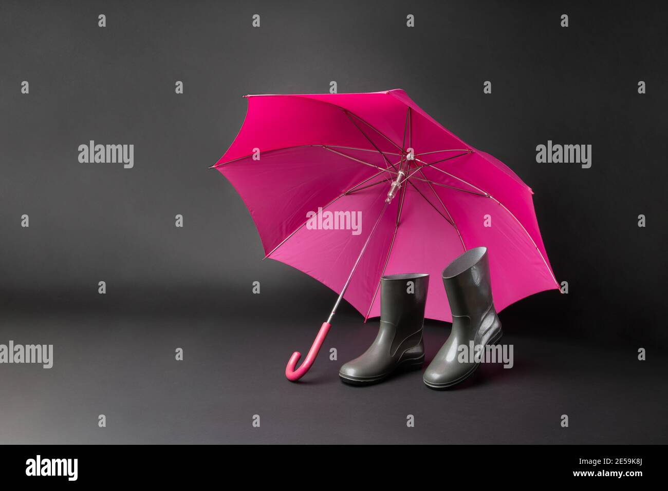Scarpe in gomma e ombrello isolati su sfondo nero. Stagione della pioggia e previsioni del tempo. Nessuno Foto Stock