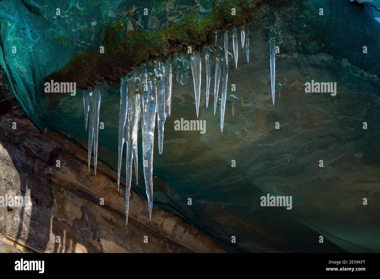 I ghiaccioli affilati appesi sul bordo del balcone. Sciogliendo la neve si forma un icicolo. Foto Stock