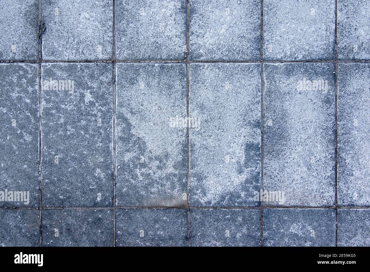 Sale spalmato su pavimenti ghiacciati in città. Mattoni coperti con macchie di sale. Marciapiede scivoloso in inverno. Foto Stock