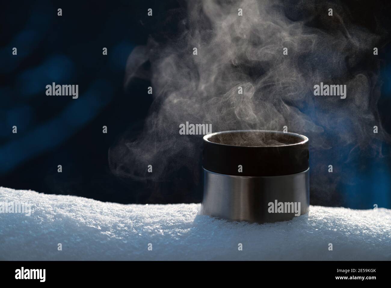 Primo piano della tazza thermos con una bevanda calda a vapore all'esterno sulla neve. Nessuno Foto Stock