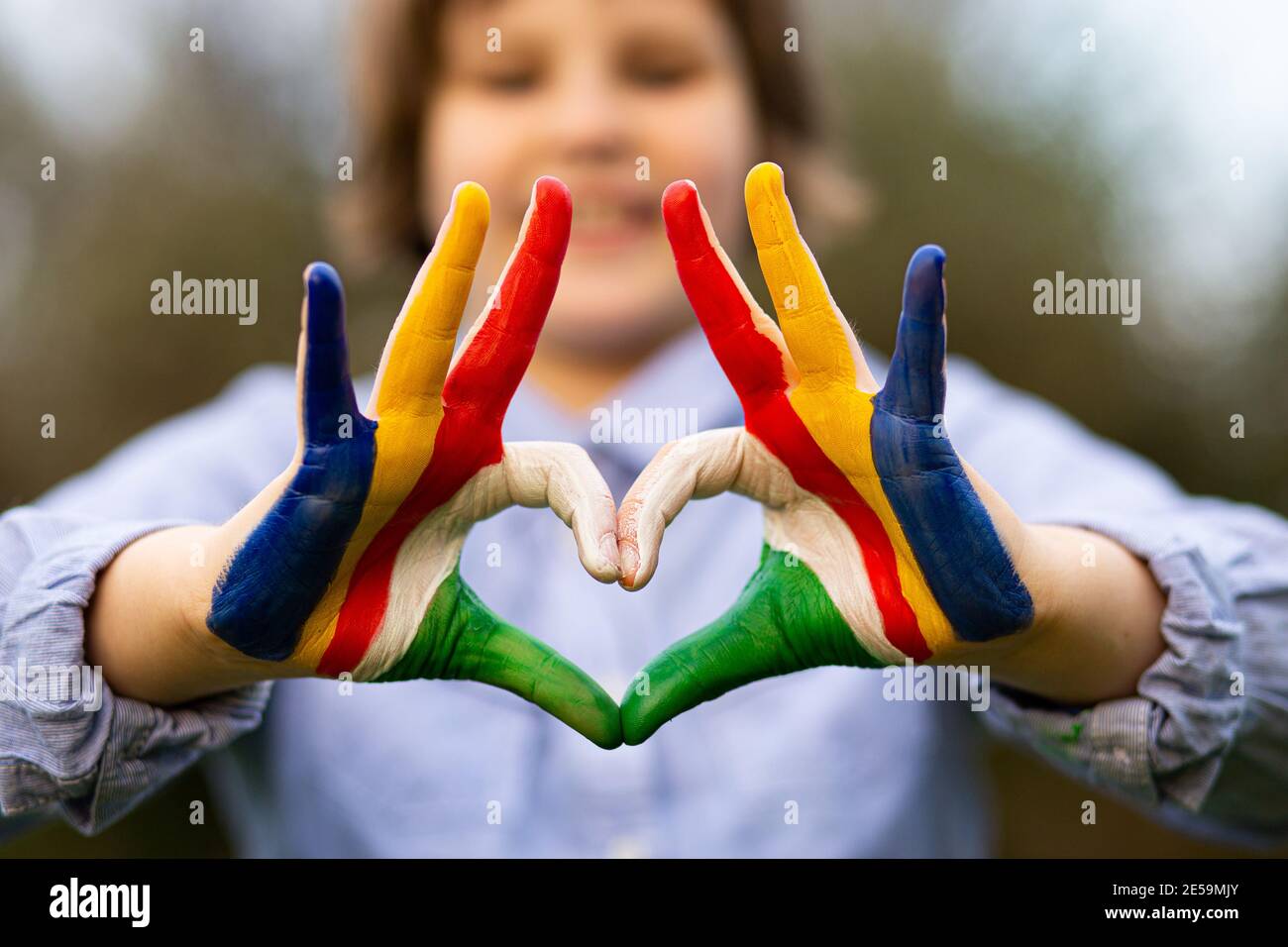 Mani di capretto dipinte in Seychelles bandiera colore mostra simbolo di il cuore e il gesto d'amore sullo sfondo della natura Foto Stock