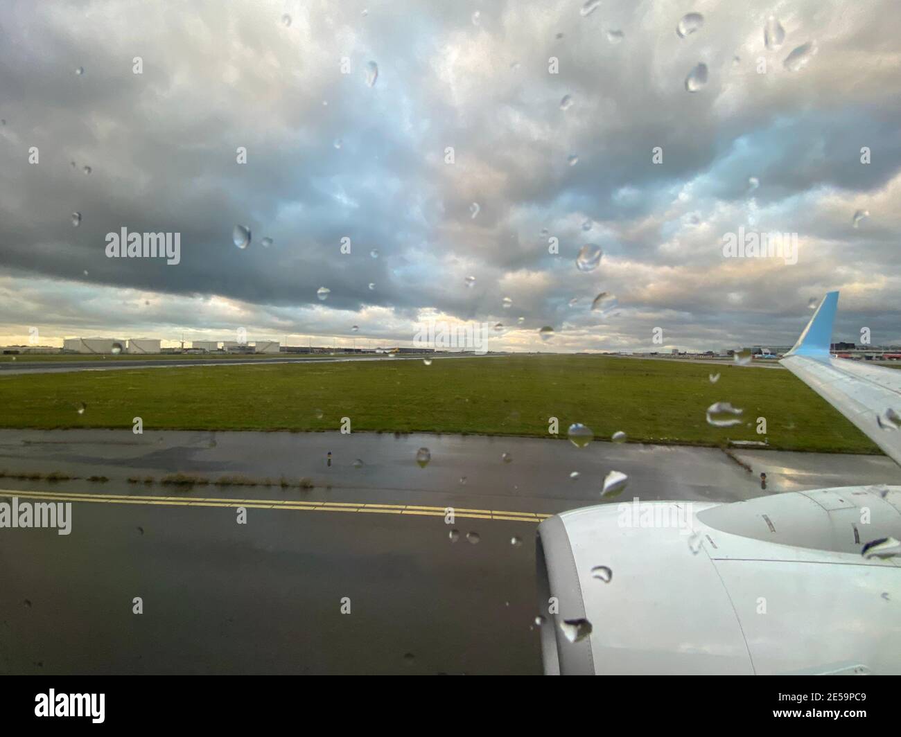 Tassare all'aeroporto in una giornata di pioggia con il maltempo. Guardando fuori dalla finestra dell'aeromobile sulla pista asfalto. Gocce di pioggia sulla finestra. Foto di alta qualità Foto Stock