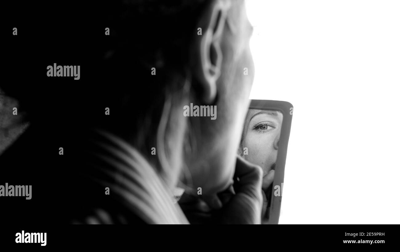 La ragazza sta facendo. Riflessione nello specchio. Gli occhi e le ciglia sono visibili. Ritratto in bianco e nero. Foto Stock