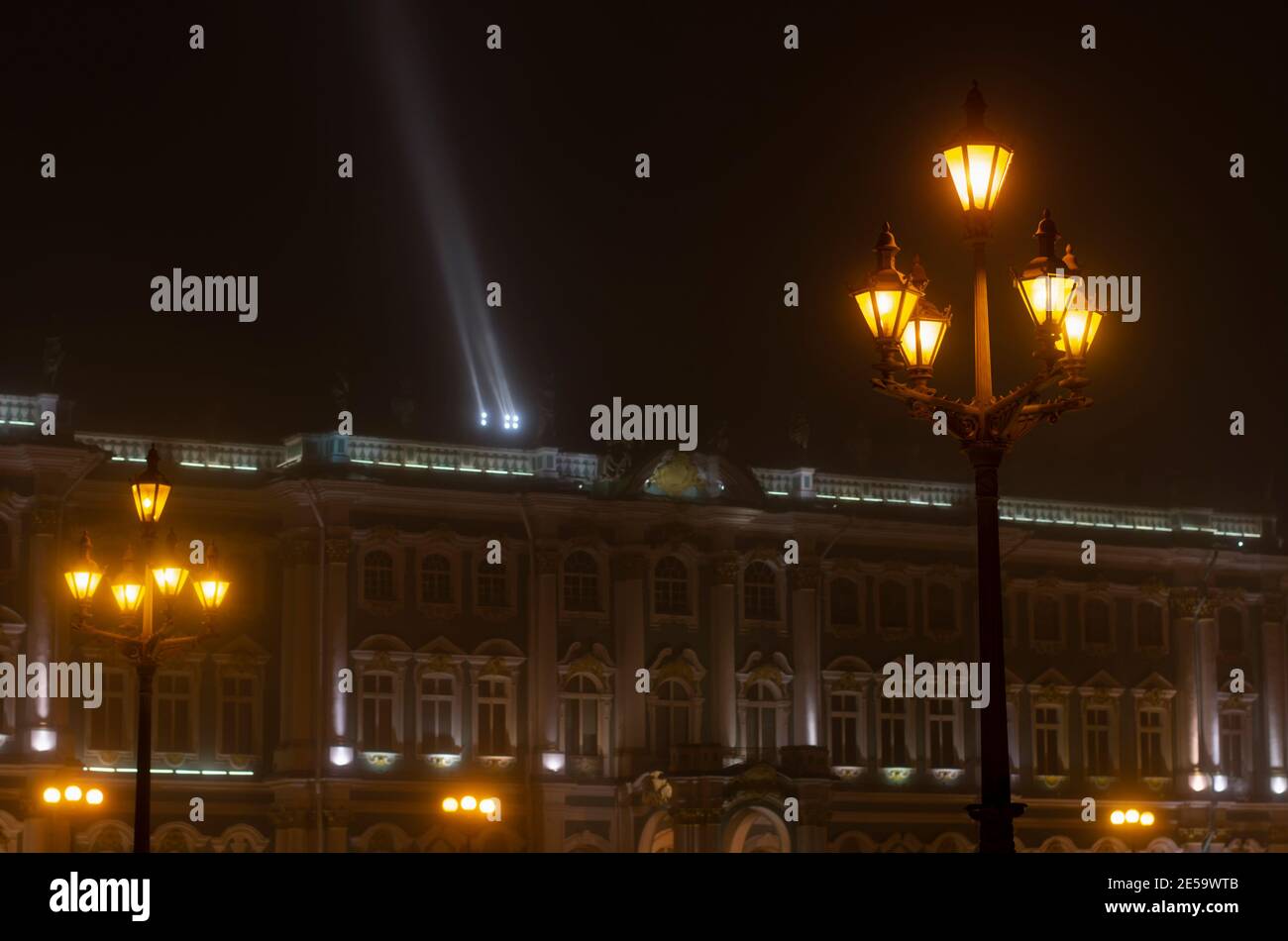 Scena notturna con lanterne in primo piano e sfondo sfocato con Palazzo d'Inverno e illuminazione serale (San Pietroburgo, Russia) Foto Stock