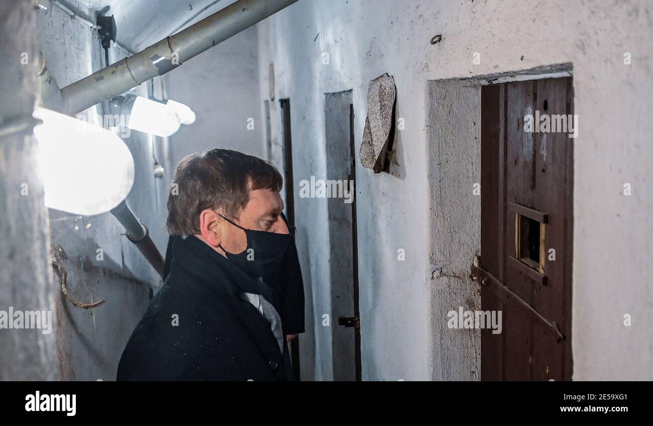 Frankenberg, Germania. 27 gennaio 2021. Michael Kretschmer (CDU), primo ministro della Sassonia, si affaccia su una cella di detenzione presso il memoriale del campo di concentramento di Sachsenburg. In occasione della giornata nazionale del ricordo delle vittime del nazionalsocialismo, Kretschmer visita il sito commemorativo dell'ex campo di concentramento nazista. Tra il 1933 e il 1937, la SA e le SS hanno imprigionato più di 2000 oppositori del regime sulla base del vecchio mulino. Credit: Hendrik Schmidt/dpa-Zentralbild/dpa/Alamy Live News Foto Stock