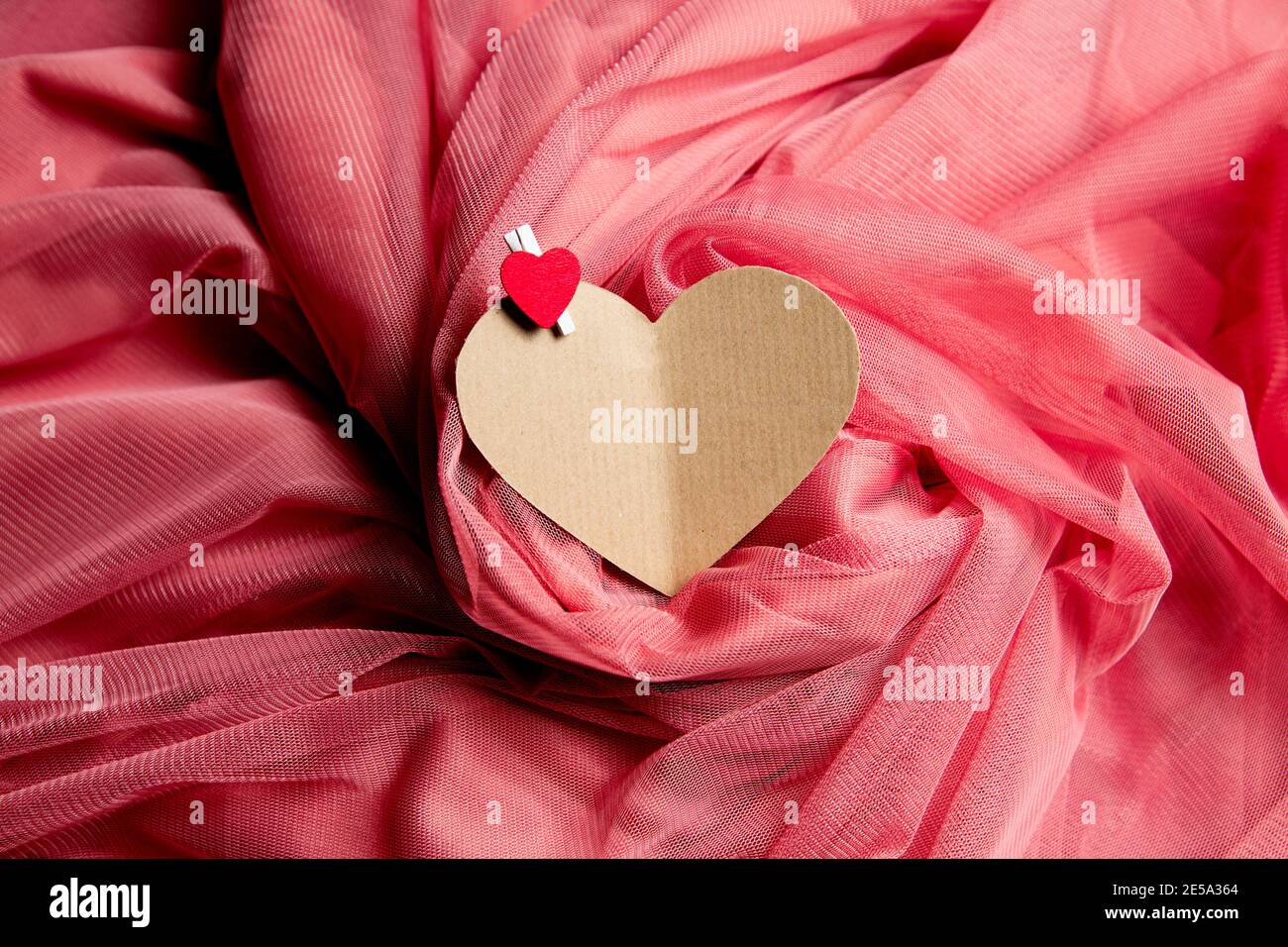 cuore di carta con stendibiancheria su panno rosa Foto Stock