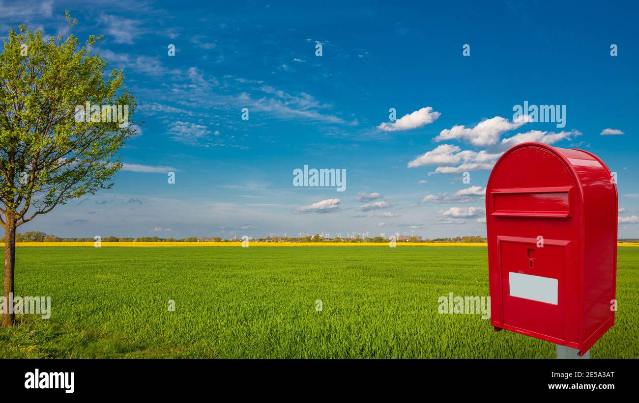 Grande postbox rosso elegante con spazio vuoto per le note l'indirizzo si trova all'aperto di fronte allo splendido paesaggio di campagna fattoria campo con giallo Foto Stock