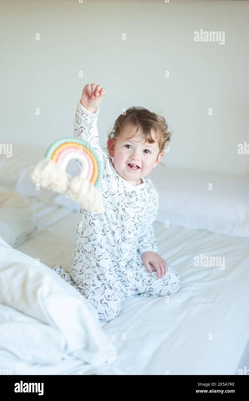 Bambina che indossa pigiami che giocano a letto Foto Stock