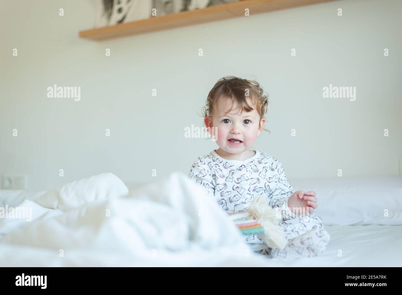 Bambina che indossa pigiami che giocano a letto Foto Stock