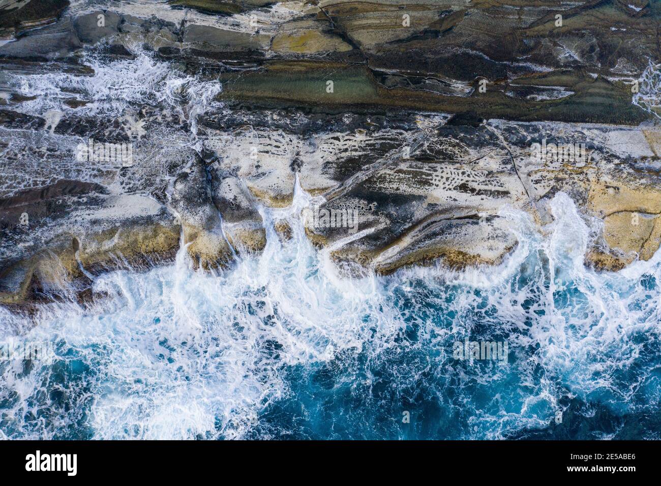 Ripresa aerea delle onde del Pacifico che si propagano sullo sperone roccioso lungo La costa dell'isola di Biri Foto Stock