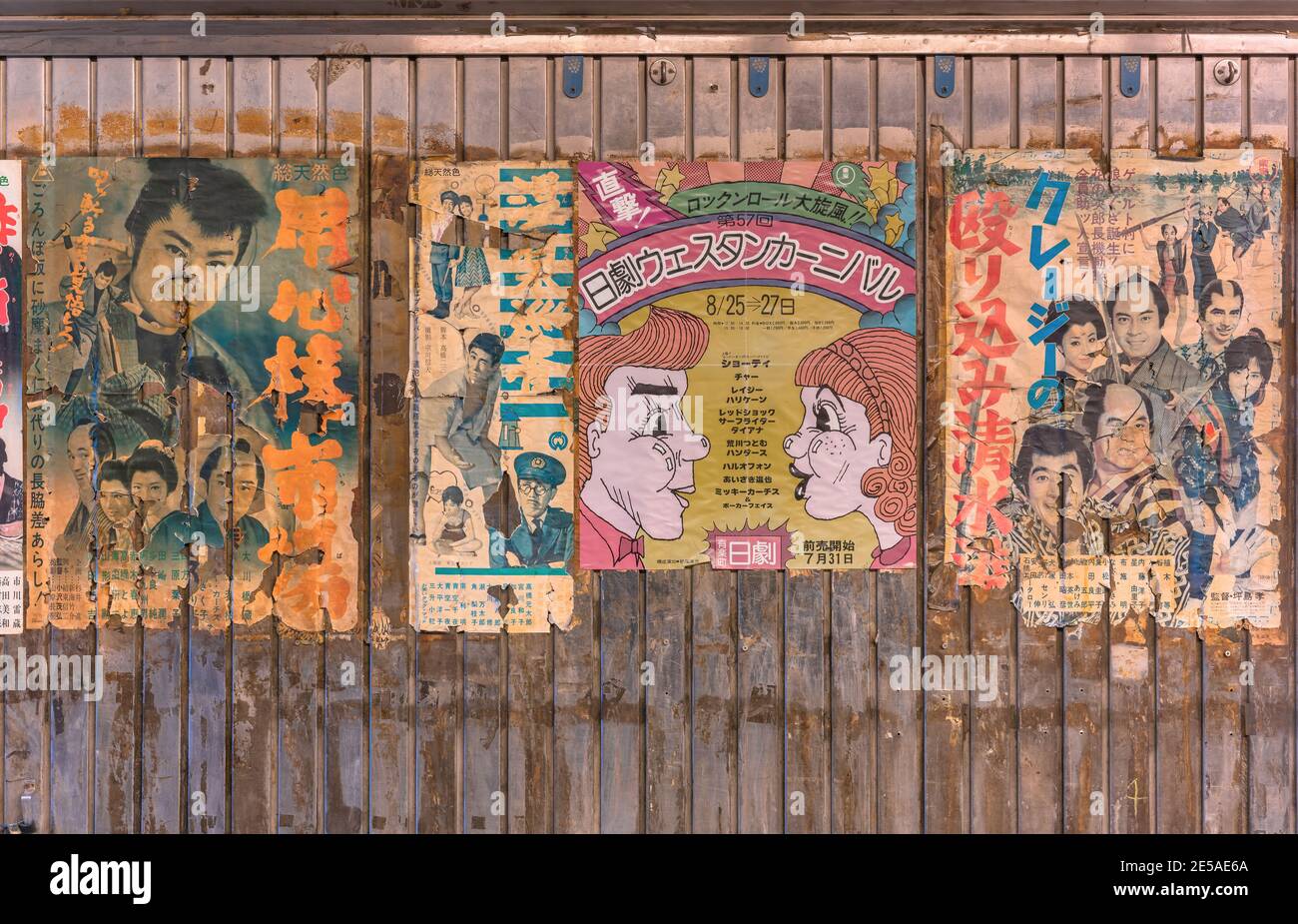 tokyo, giappone - gennaio 26 2021: Strappati vecchi poster giapponesi d'epoca di film retrò samurai e concerto di musica rock e roll incastrato sul muro arrugginito di Foto Stock