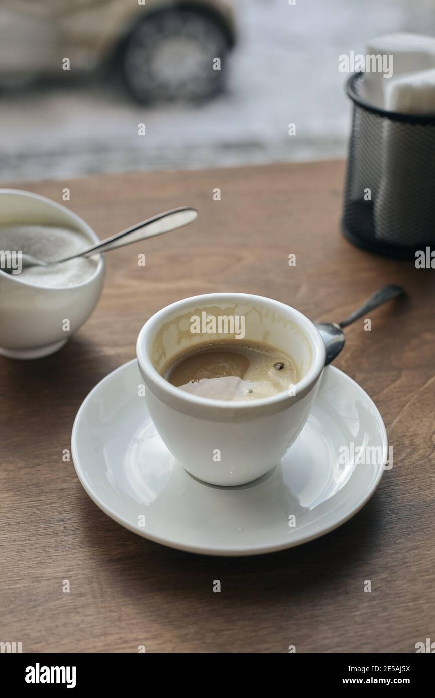 Mezza beve il caffè in una tazza di caffè bianca sul tavolo. Foto Stock