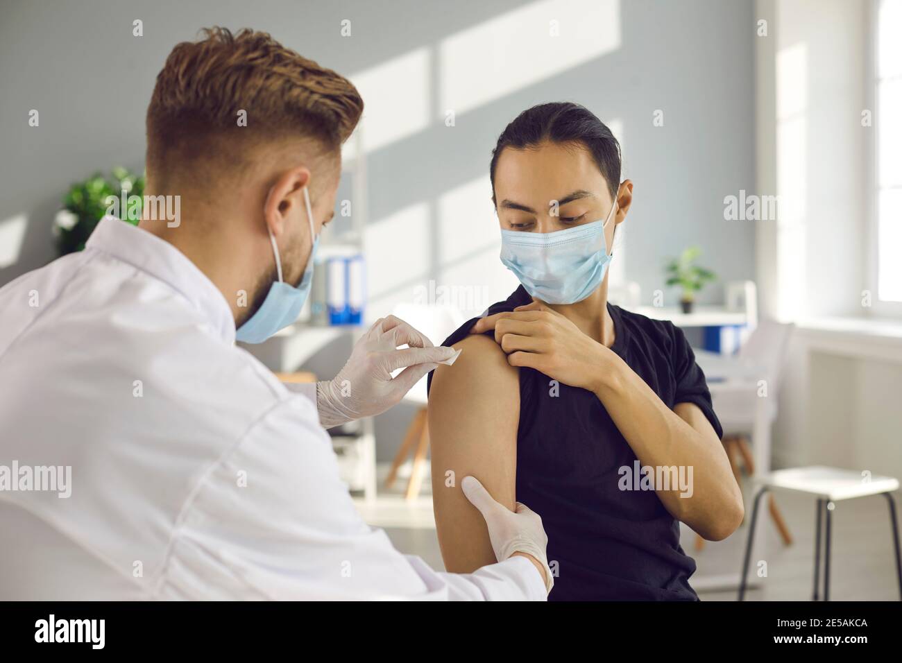 Giovane uomo in maschera medica viso ottenere stagionale influenza shot O vaccino moderno Covid-19 Foto Stock