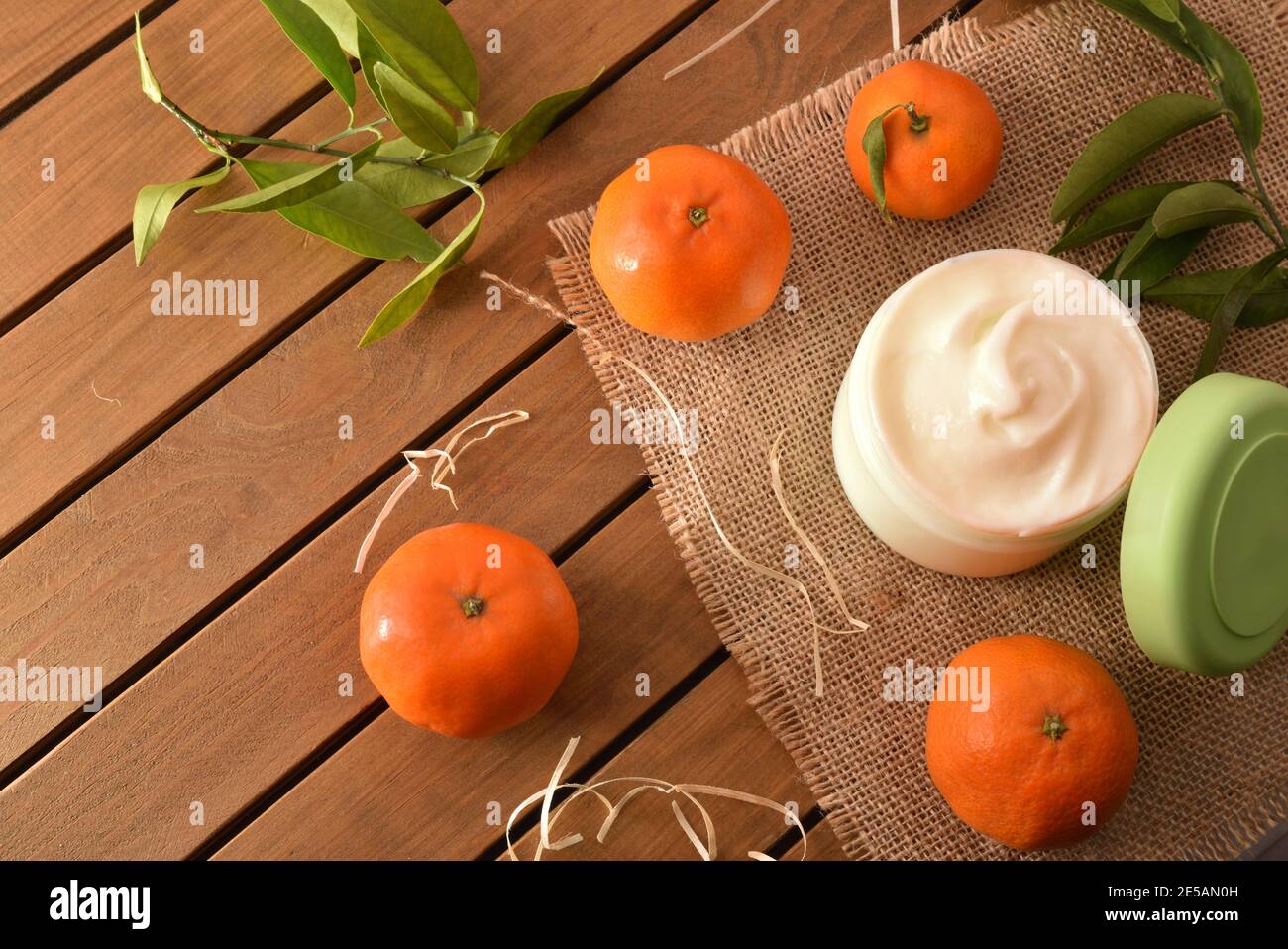 Crema cosmetica naturale di mandarino su tavola di legno con frutta e foglie. Vista dall'alto. Foto Stock