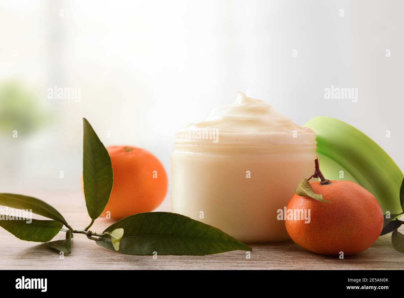Crema naturale di pelle con estratto di mandarino con frutta e foglie su tavola di legno. Vista frontale. Foto Stock
