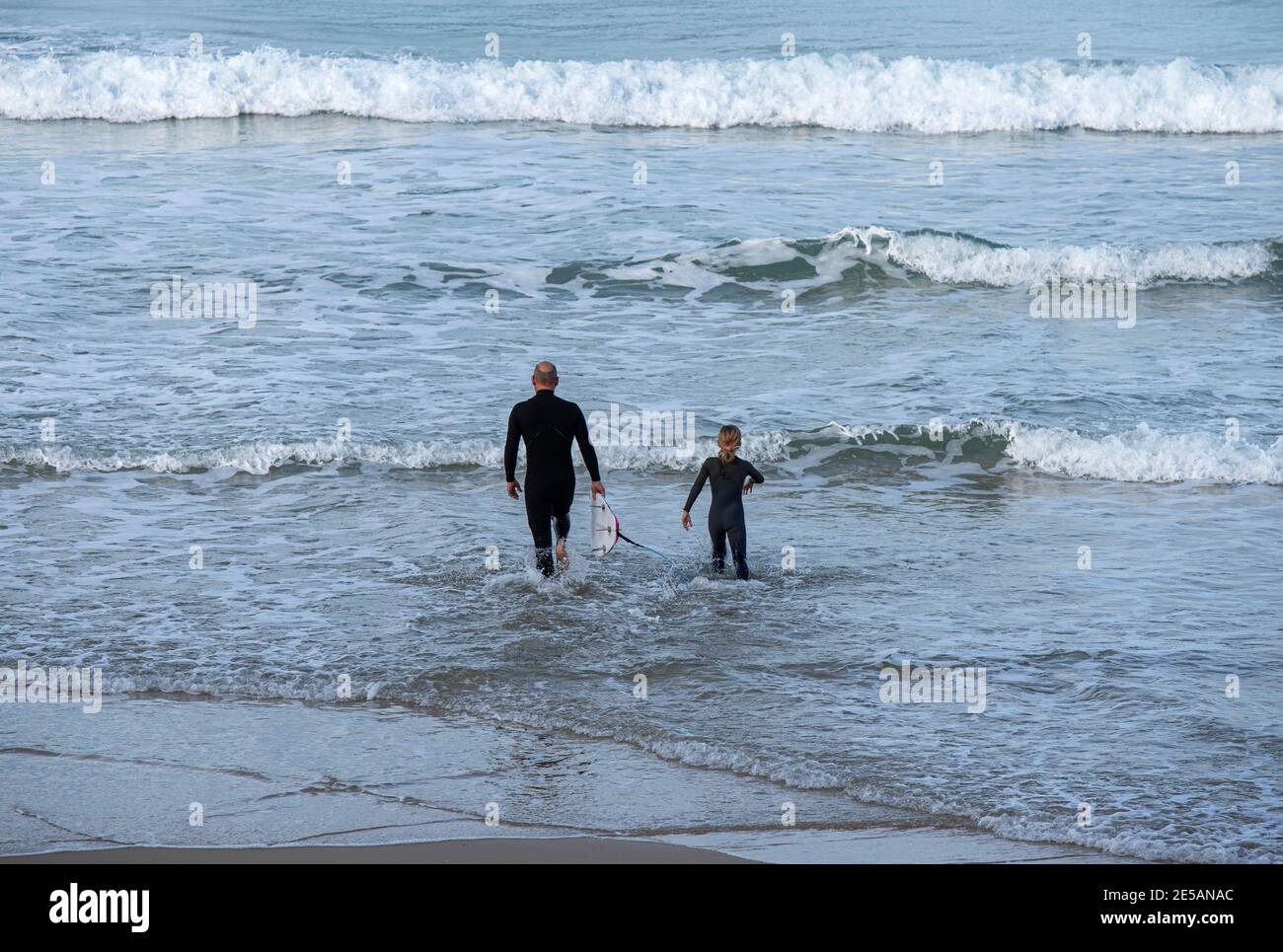 la famiglia entra in mare per fare surf Foto Stock