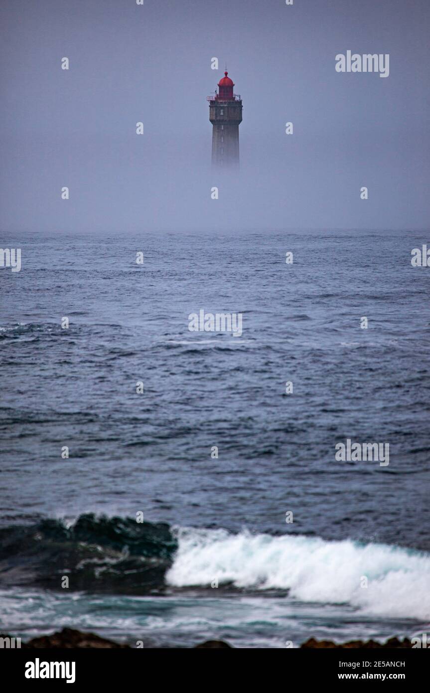 Il drammatico faro la Jument, circondato dalla nebbia estiva, al largo della costa dell'Ile d'Ouessant, Bretagna. L'iconico faro alto 47 metri era bui Foto Stock