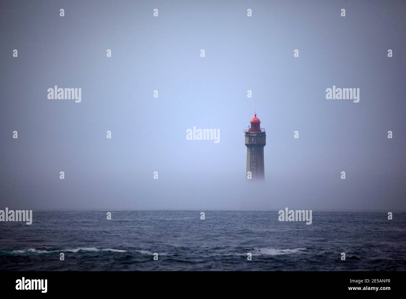 Il drammatico faro la Jument, circondato dalla nebbia estiva, al largo della costa dell'Ile d'Ouessant, Bretagna. L'iconico faro alto 47 metri era bui Foto Stock