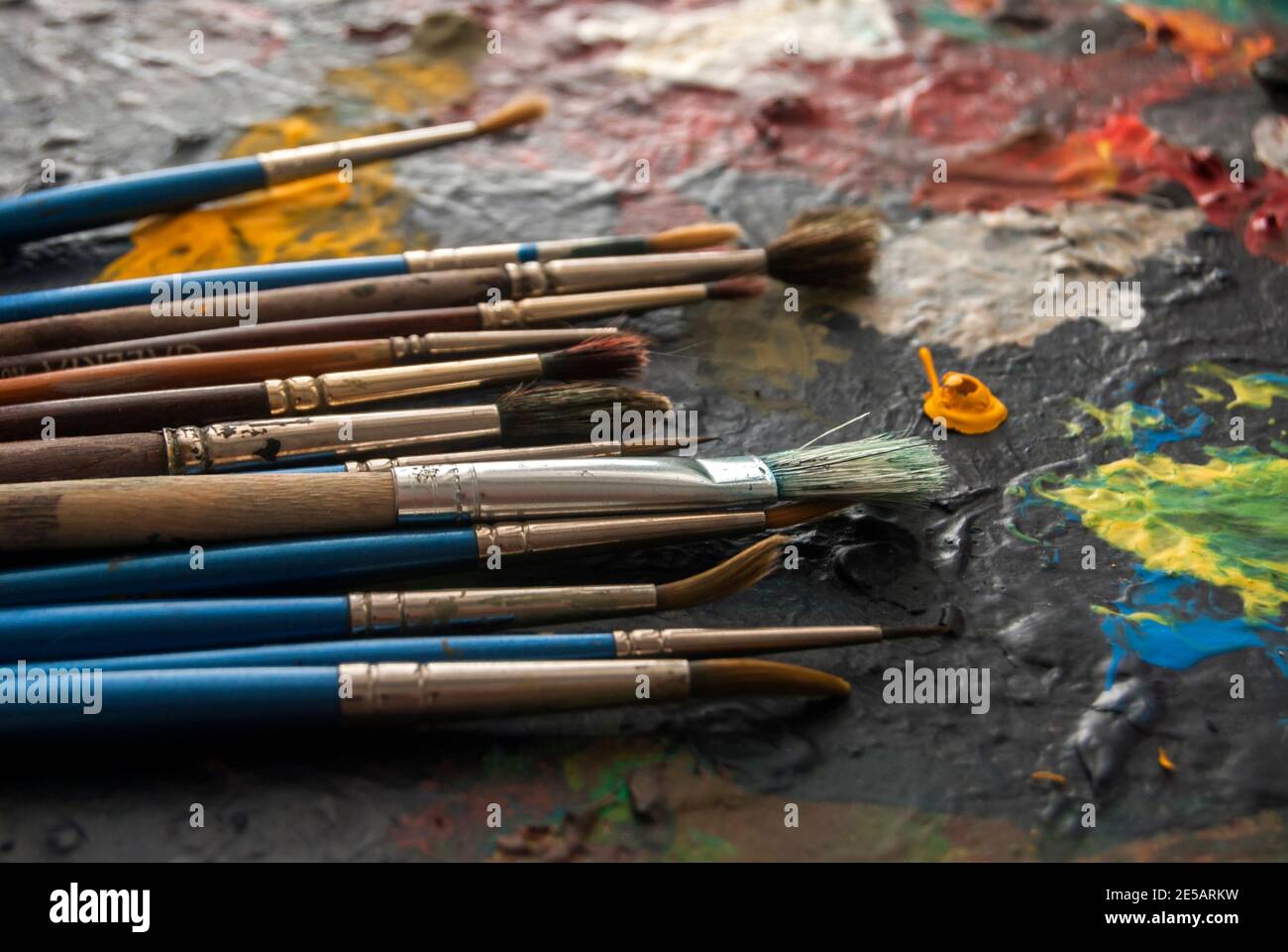 Utilizzato diversi tipi di pennelli di vernice su colorato closeup di tavolozza atrist Foto Stock