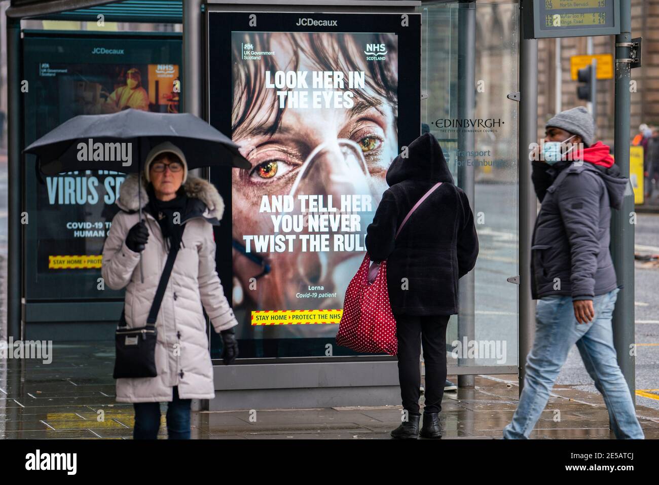 Edimburgo, Scozia, Regno Unito. 27 gennaio 2021. I membri del pubblico camminano oggi oltre il nuovo governo Covid-19 manifesti di avvertimento di salute su Princes Street a Edimburgo. Iain Masterton/Alamy Live News Foto Stock