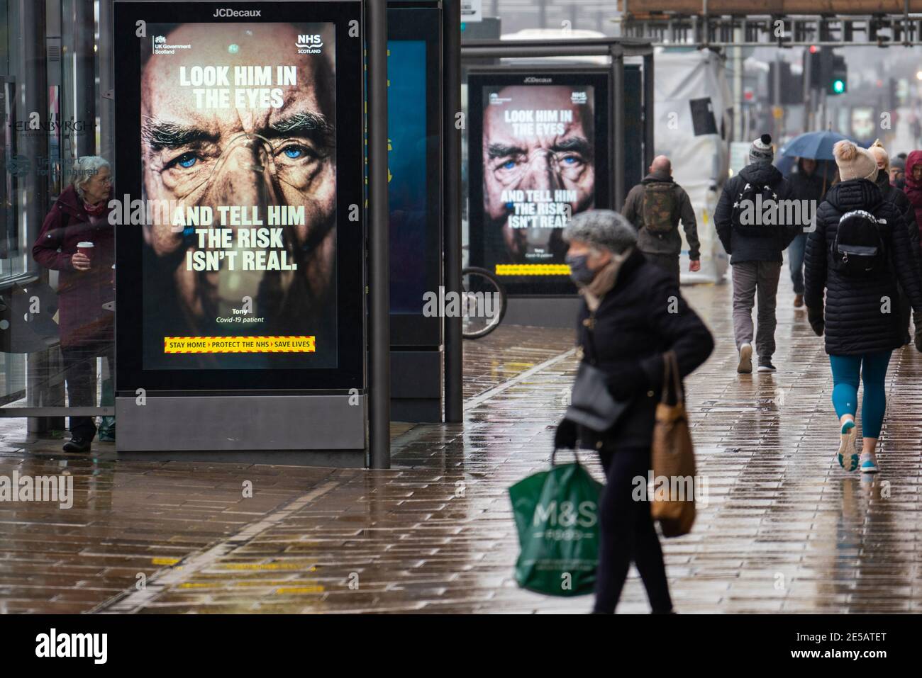 Edimburgo, Scozia, Regno Unito. 27 gennaio 2021. I membri del pubblico camminano oggi oltre il nuovo governo Covid-19 manifesti di avvertimento di salute su Princes Street a Edimburgo. Iain Masterton/Alamy Live News Foto Stock