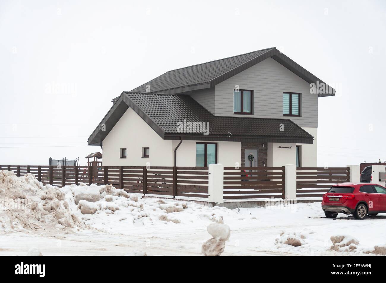Krasnodar, Russia - Gennaio 23 2021: Casa privata a due piani circondata da una recinzione e una macchina rossa Foto Stock