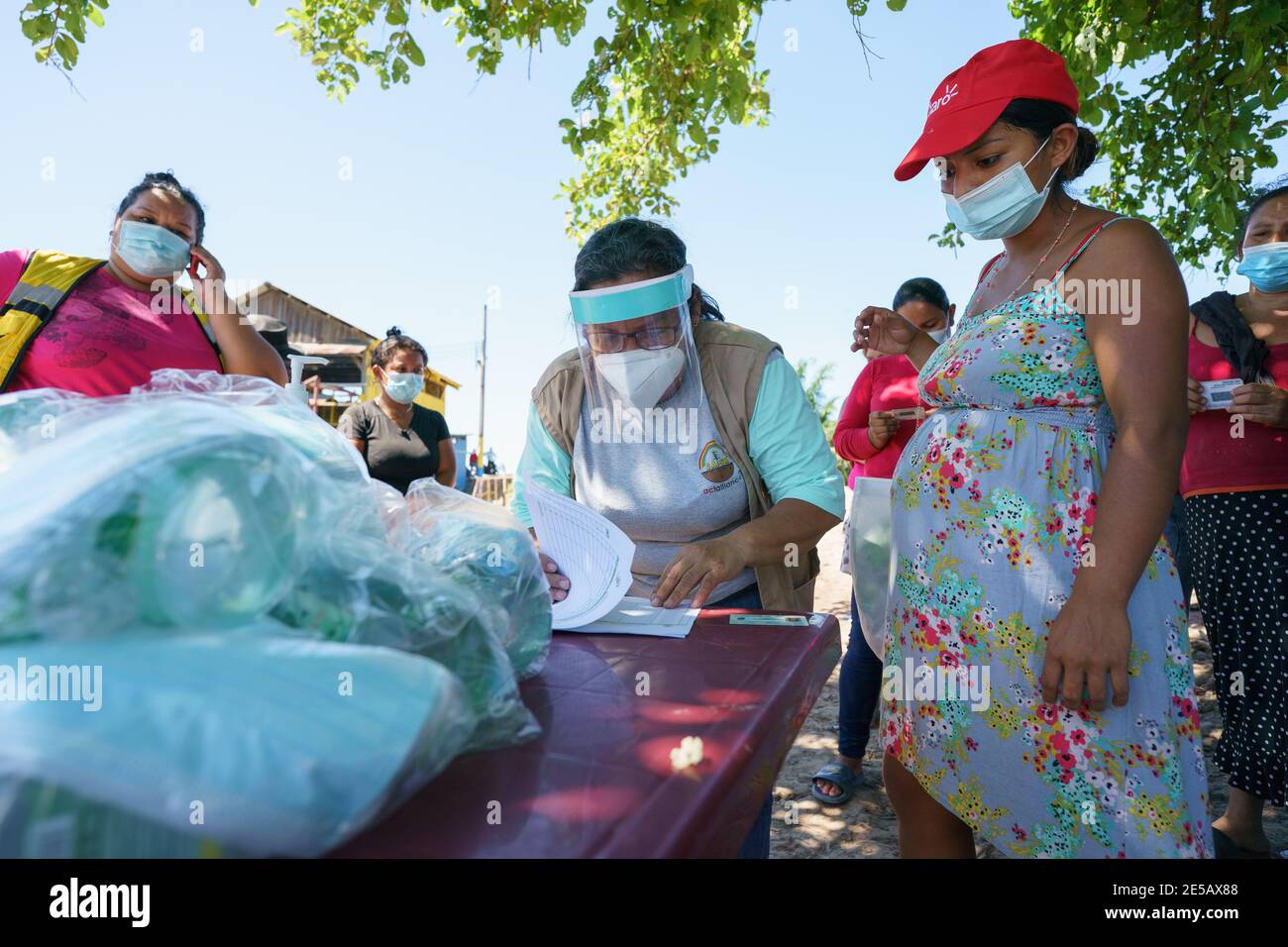 Bellingham, Washington, Stati Uniti. 26 gennaio 2021. IL PASTORE MARIA HERNANDEZ firma un registro di aiuti per ricevere sacchi da 70 libbre (32 kg) di prodotti alimentari nella comunità di posa de Rio vicino a Choloma, Honduras, martedì 26 gennaio 2021. Molte delle case delle 62 famiglie di questa comunità sono state danneggiate o distrutte quando le acque alluvionali del fiume ChamelecÃ³n rigonfiato da Hurricanes ETA e Iota nel novembre del 2020 hanno violato le dighe che circondano la comunità.la distribuzione di aiuti di cibo e kit di prevenzione COVID è stata finanziata da Lutheran World Relief e coordinato dall'agenzia locale CASM, con distribuzione sup Foto Stock