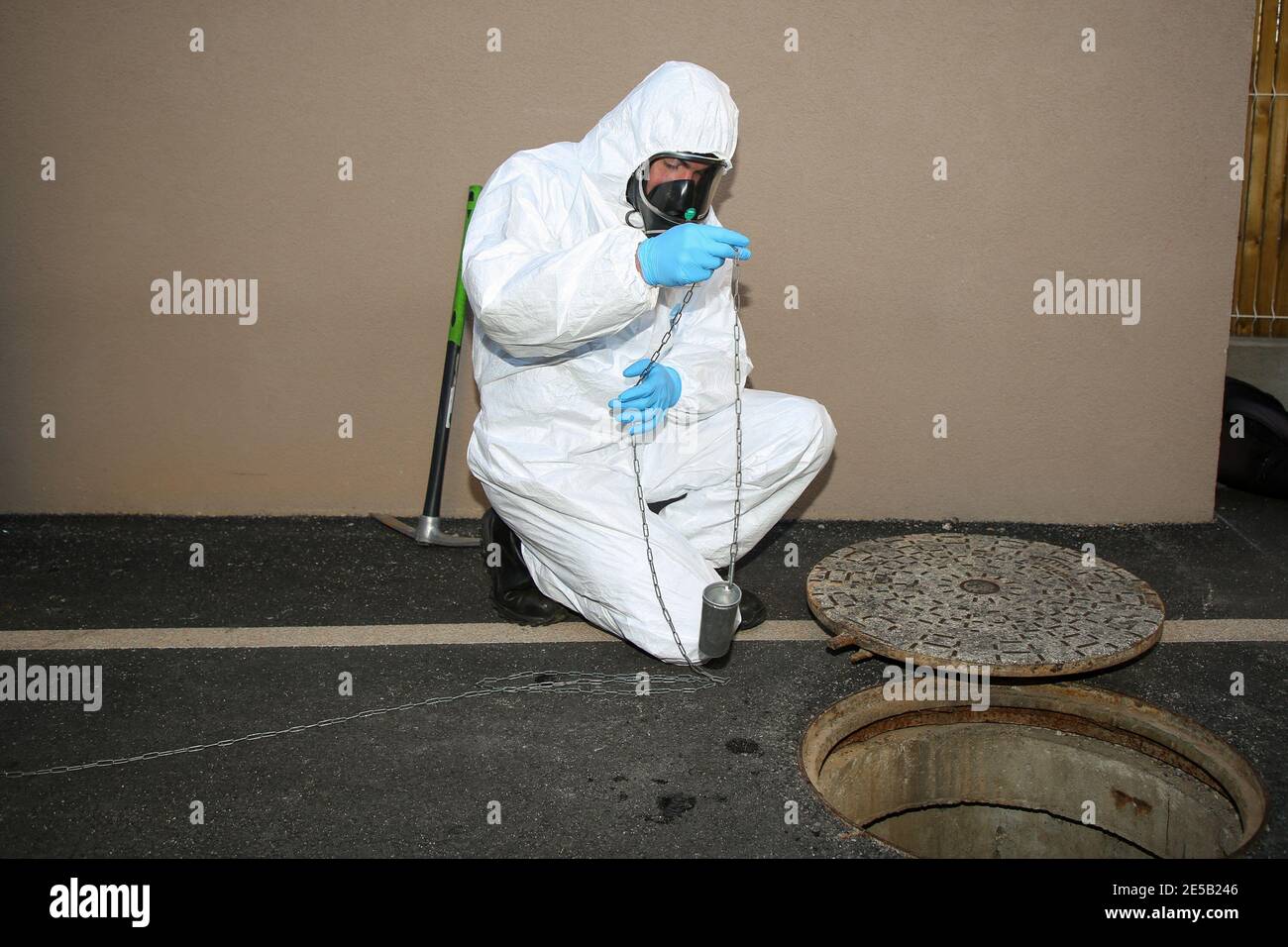 Marsiglia, Francia. 26 gennaio 2021. Un operatore sanitario che indossa una tuta per dispositivi di protezione individuale (DPI) preleva un campione durante il test delle acque reflue. L'unità COMETE (Covid Marseille Environmental Testing Expertise) raccoglie campioni di acque reflue in vari punti della città per determinare i quartieri, le scuole o alcuni edifici contaminati da Covid-19 attraverso il test di questi campioni. Credit: SOPA Images Limited/Alamy Live News Foto Stock