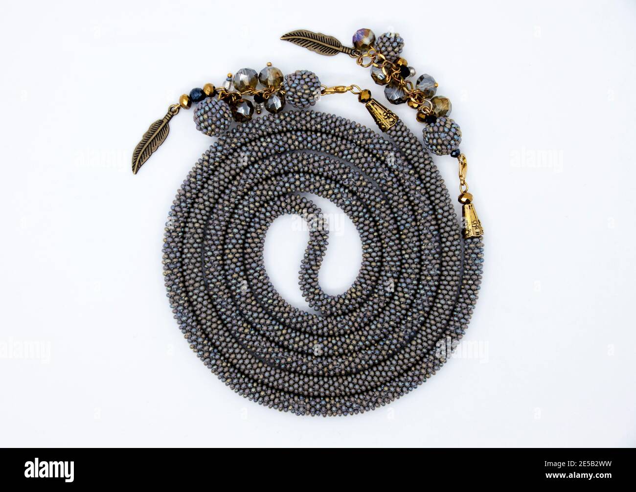 Una collana fatta di belle perle giace in una spirale avvolta su una superficie bianca. Foto Stock