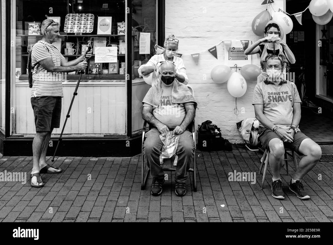 Gli uomini che hanno i loro capelli si sono radunati fuori per raccogliere i soldi per la carità di cura del cancro di Macmillan, High Street, Lewes, Sussex orientale, Regno Unito. Foto Stock