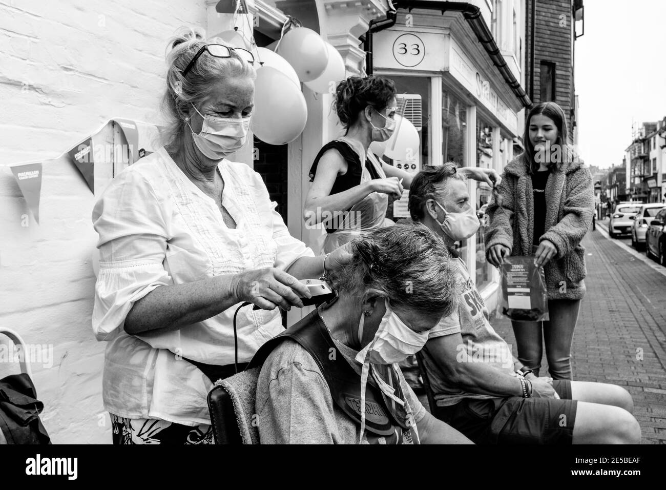 La gente che ha i loro capelli si è rasata fuori per raccogliere i soldi per la carità di cura del cancro di Macmillan, High Street, Lewes, Sussex orientale, Regno Unito. Foto Stock