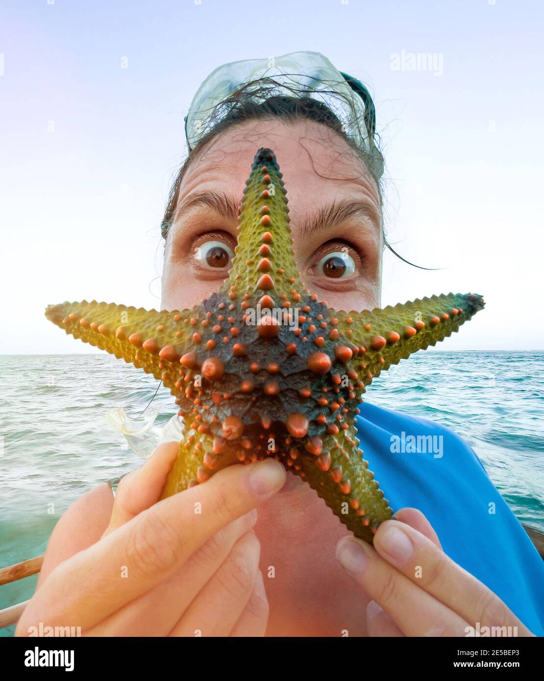 Donna che mostra una stella verde e facendo uno stupito occhi sorpresi. Immagine esotica concetto di vacanza. Foto Stock