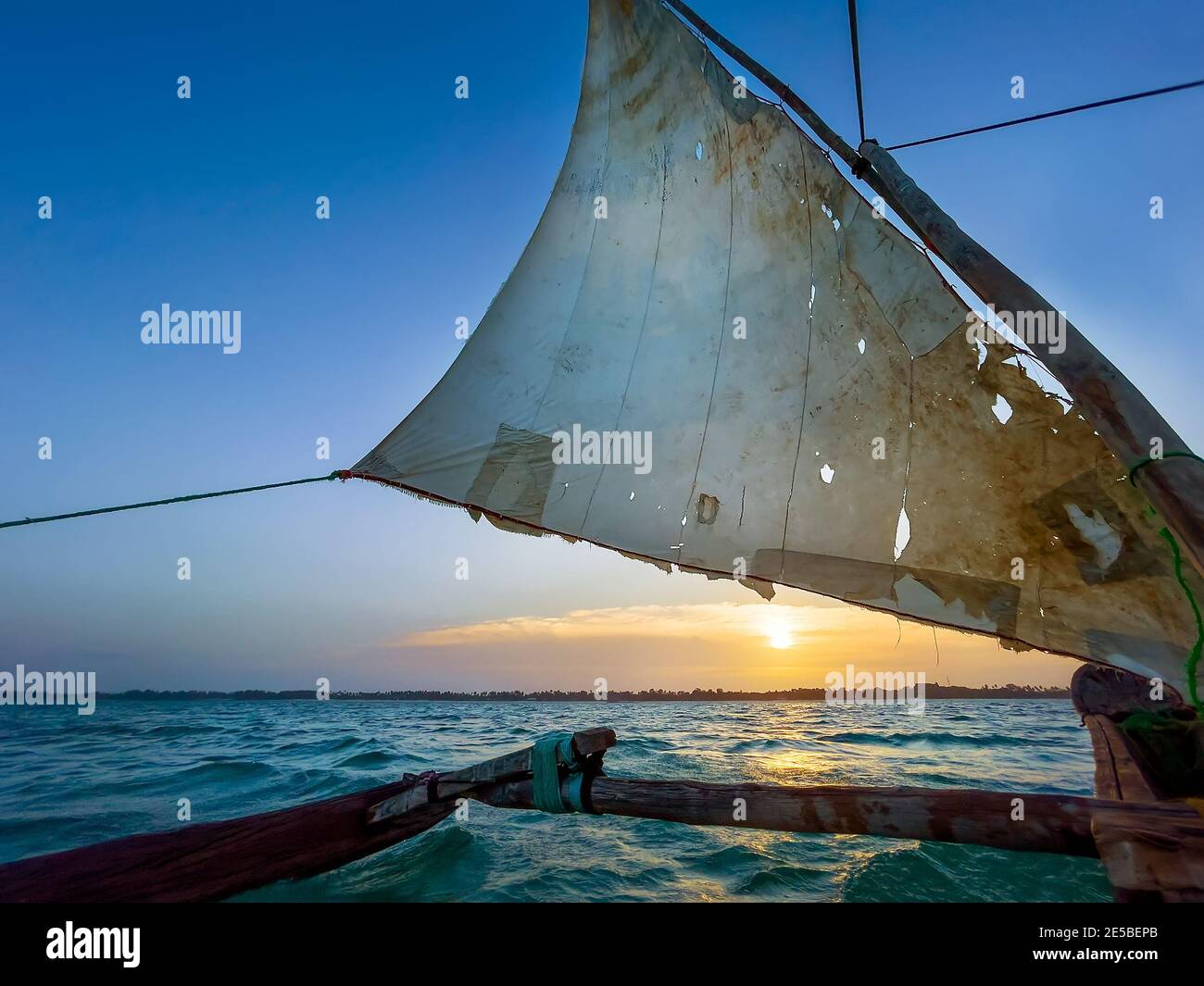 Vecchia tradizionale nave marittima tradizionale barca dhow vela sotto vela tornata nel mare indiano aperto vicino Zanzibar isola in bellissimo tramonto, Tan Foto Stock