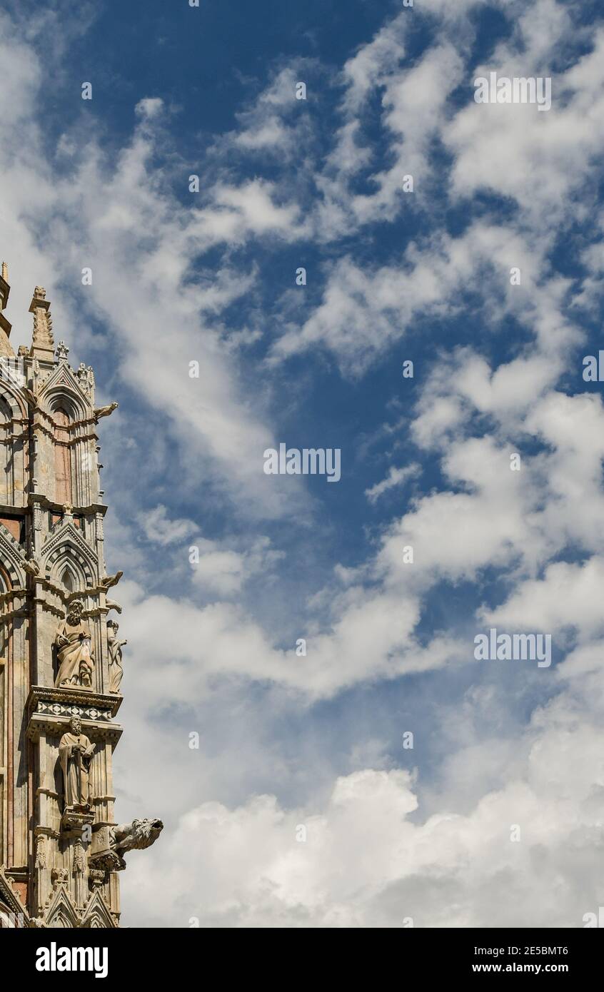 Dettagli architettonici della Cattedrale Metropolitana di Santa Maria Assunta sullo sfondo blu del cielo nuvoloso, Siena, Toscana, Italia Foto Stock