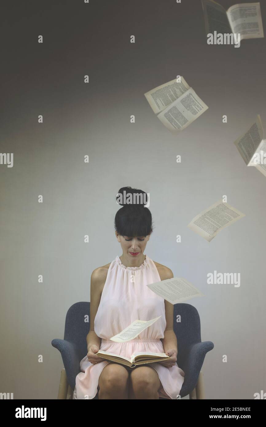 momento surreale di una donna che, leggendo un libro, le pagine galleggiano in aria Foto Stock