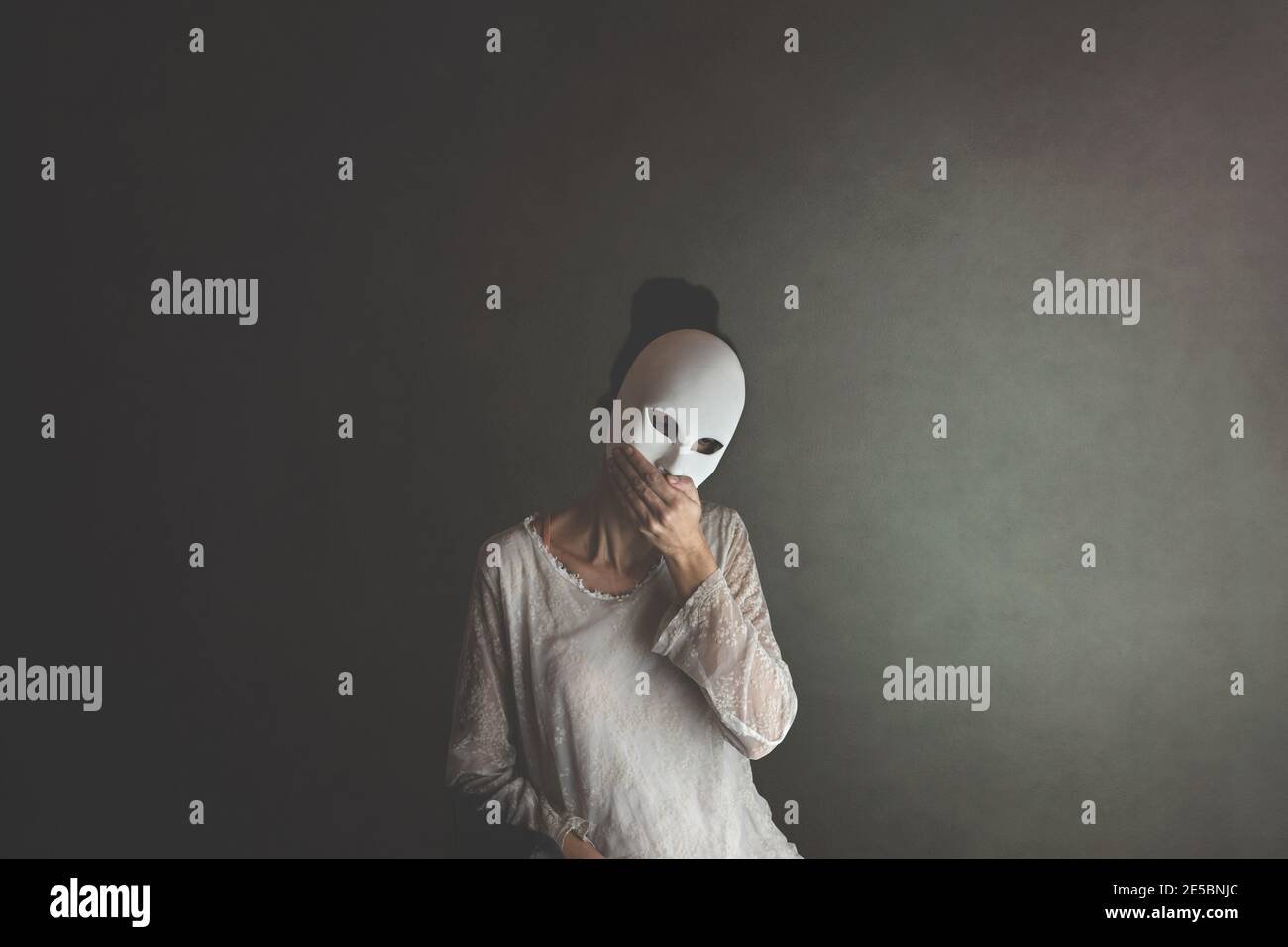 donna copre il suo viso con una maschera per proteggersi e copre la sua bocca con una mano così come non per parlare Foto Stock