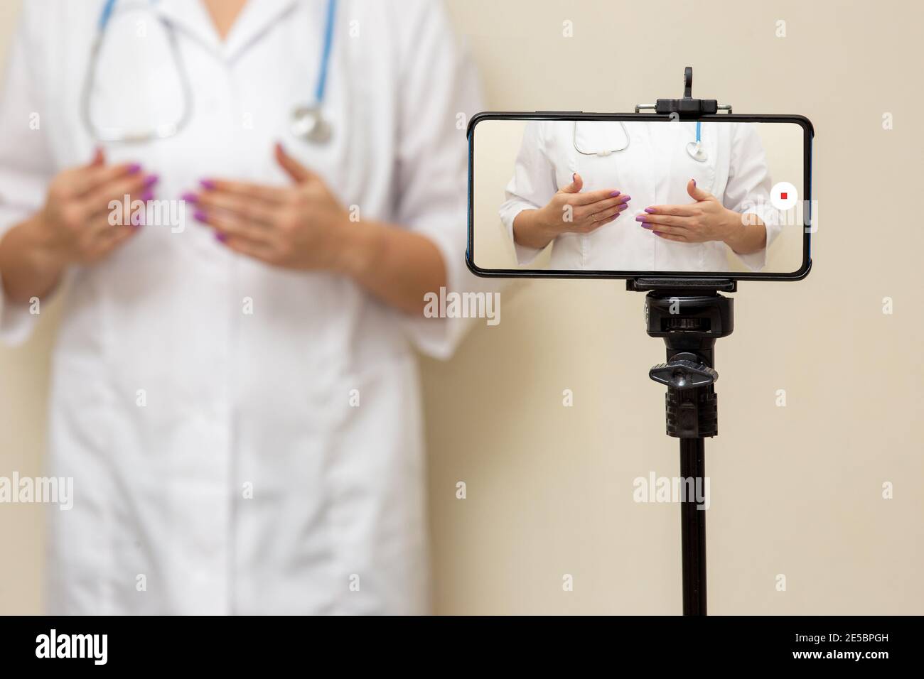 Femmina medico blogger registrazione video su uno smartphone in piedi su un treppiede. Foto Stock
