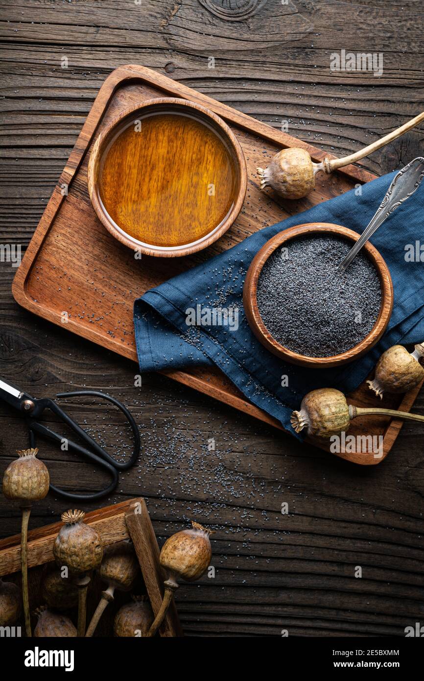 Olio di semi di papavero pressato freddo organico in una ciotola sopra uno sfondo di legno Foto Stock