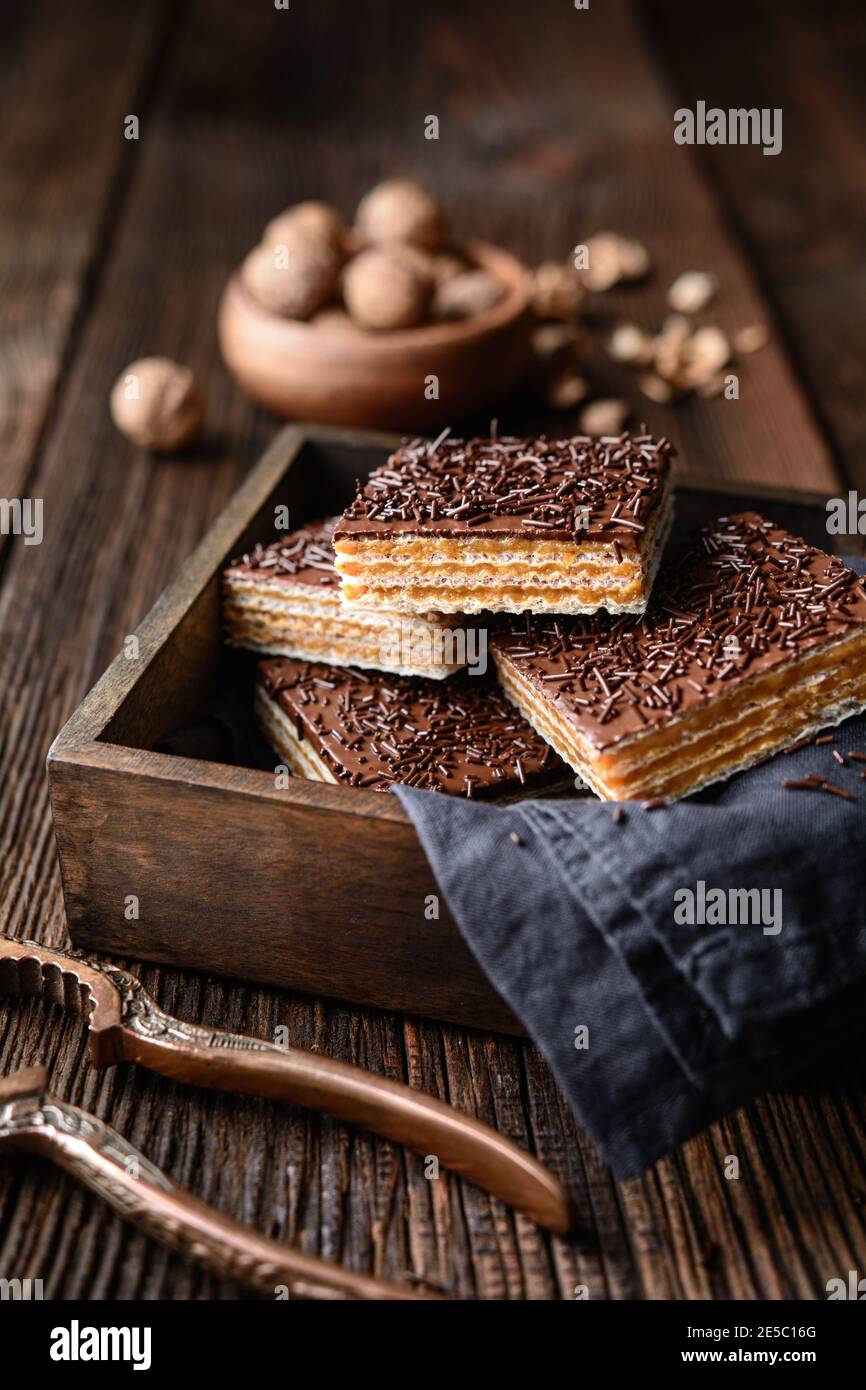 Cialda dolce fatta in casa, ripiena di noci e ricoperta con glassa di cioccolato su sfondo di legno Foto Stock