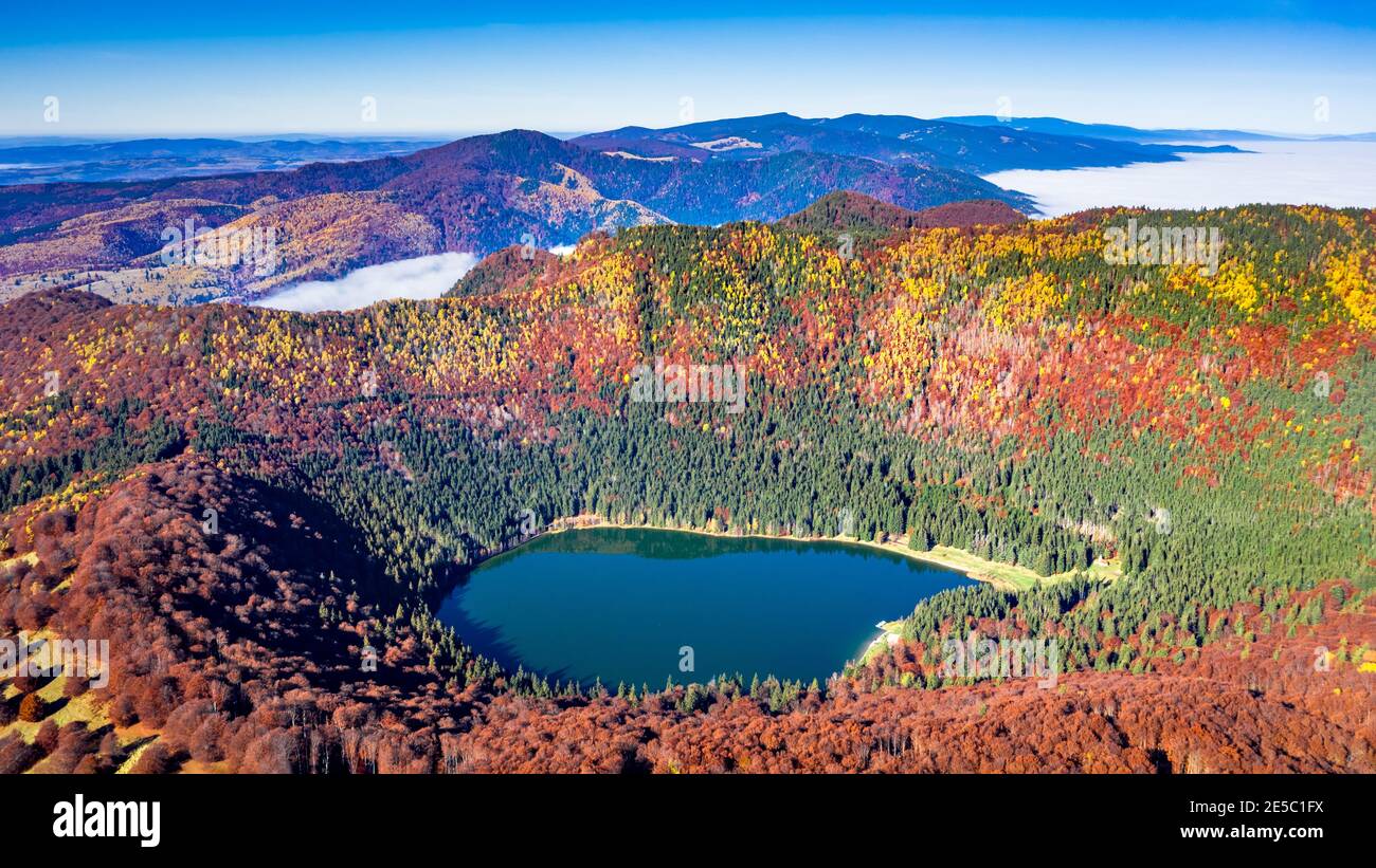 Lago di Sant'Ana, Transilvania, Romania, Europa. Splendido scenario autunnale con foresta colorata e idilliaco lago vulcanico, un popolare viaggio turistico Foto Stock