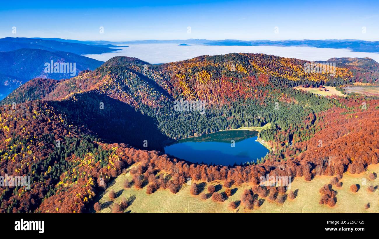 Lago di Sant'Ana, Transilvania, Romania. Splendido scenario autunnale con foresta colorata e idilliaco lago vulcanico, un popolare destinazione turistica e di viaggio Foto Stock